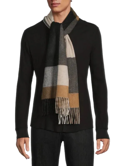 Person wearing a black sweater and a checkered scarf with fringes on a white background