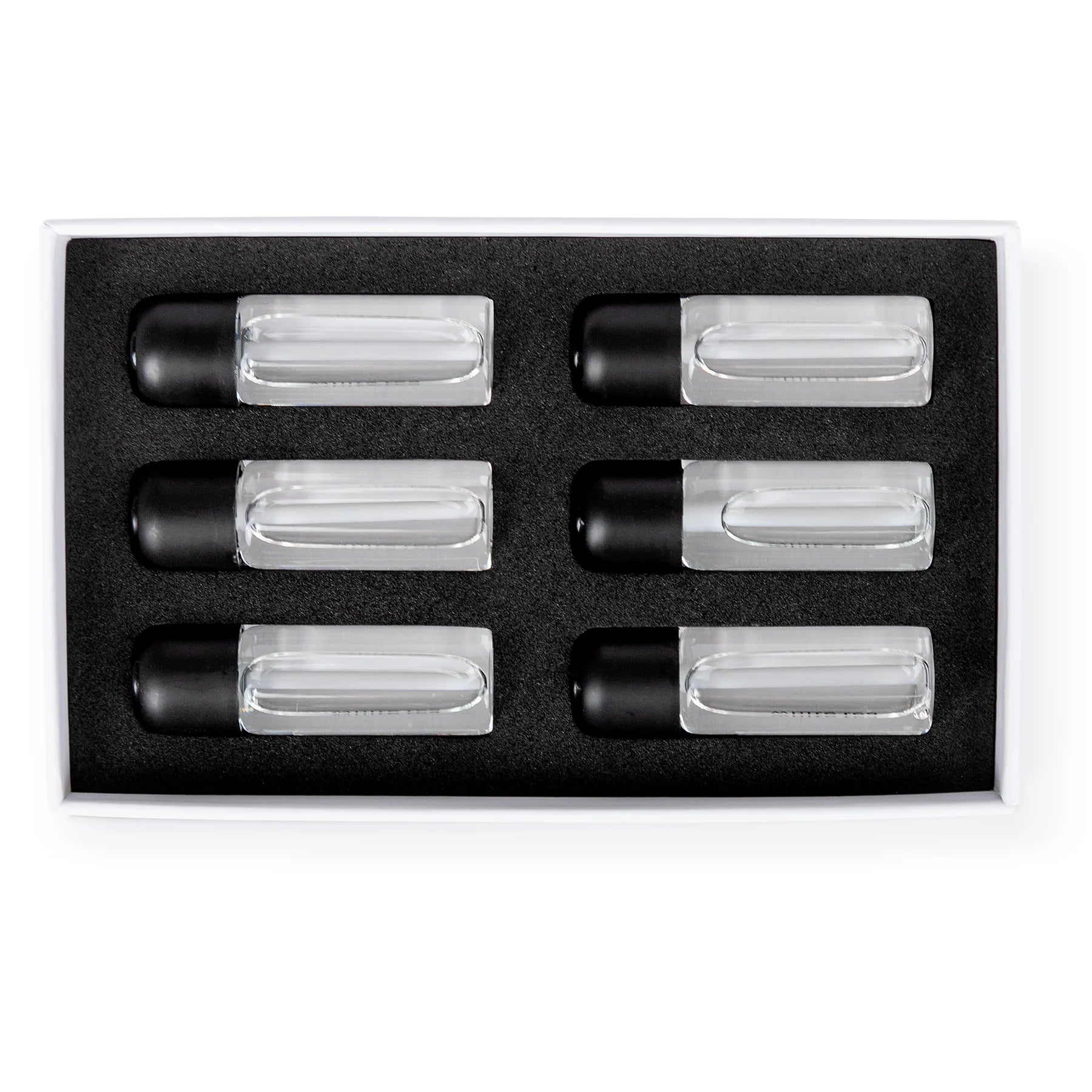 Set of six clear cylindrical containers with black lids in a black box on a white background